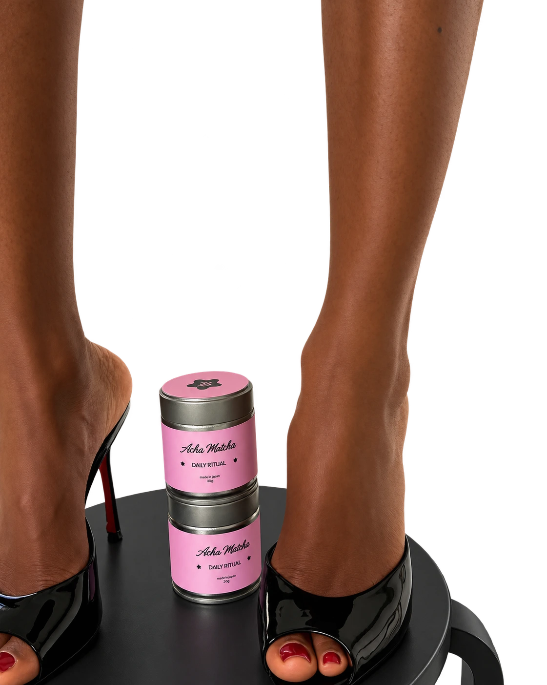 Two pink tins styled between Nessa's black heels