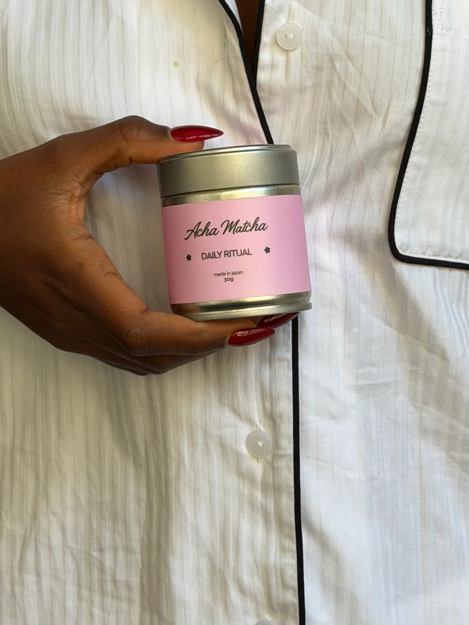 A hand holding Daily Ritual against white pyjamas